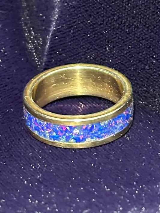24 karat gold plated over over 925 silver ring with a blue Opal inlay on a dark textured background