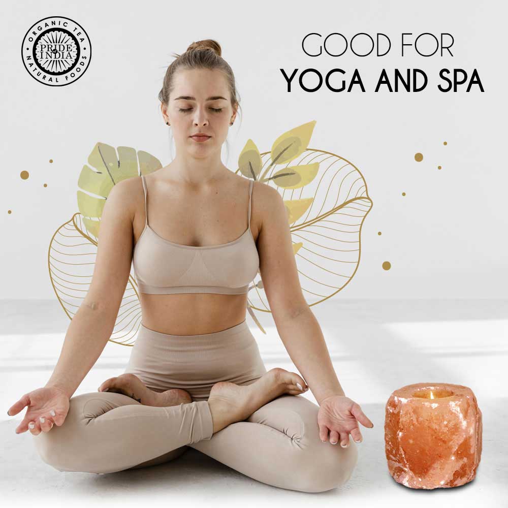 Young woman in beige loungewear meditating next to a glowing Himalayan salt lamp for mindfulness and zen decor.