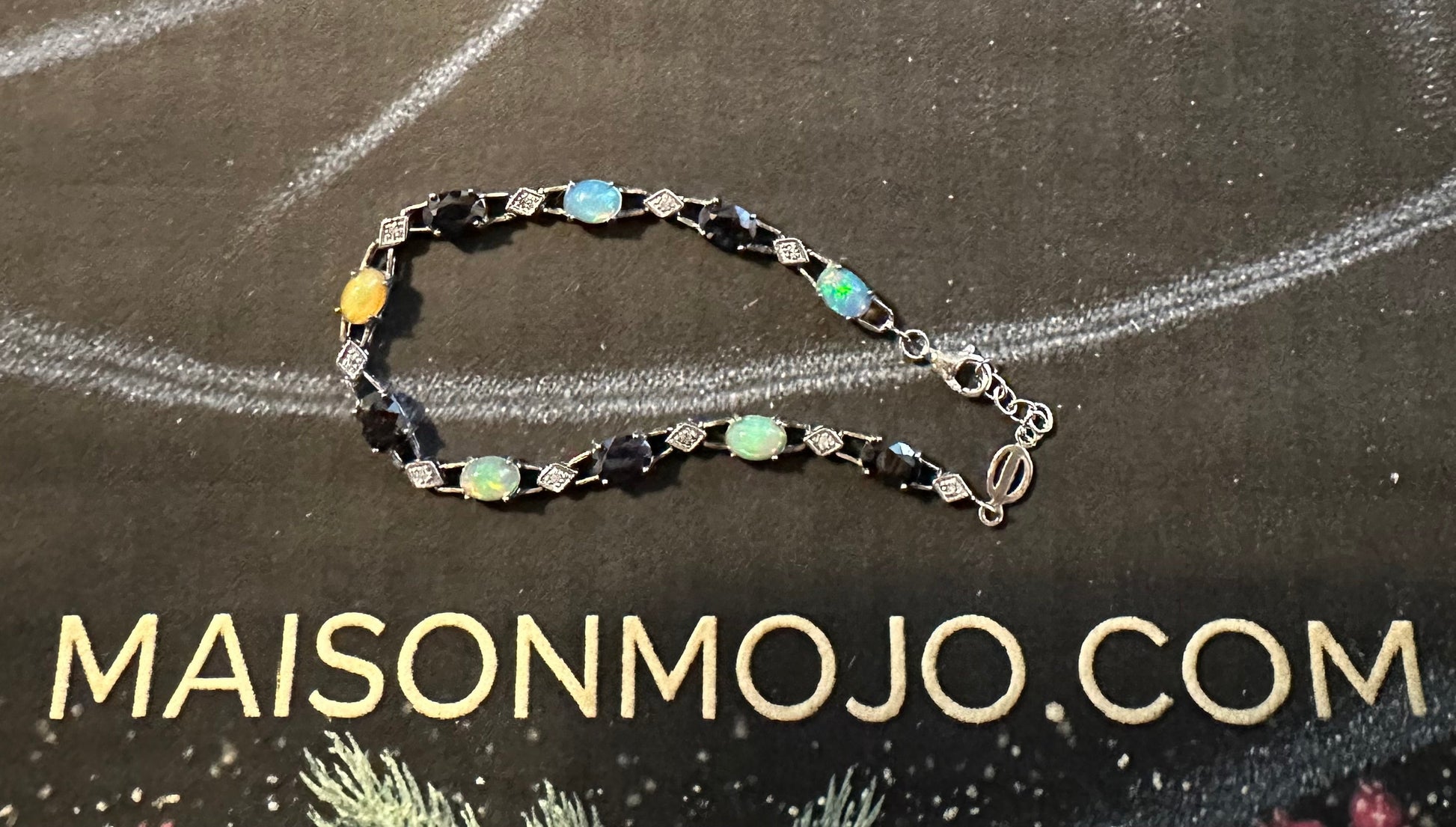 Bracelet on a black card with 'MAISONMOJO.COM' text, decorative elements around