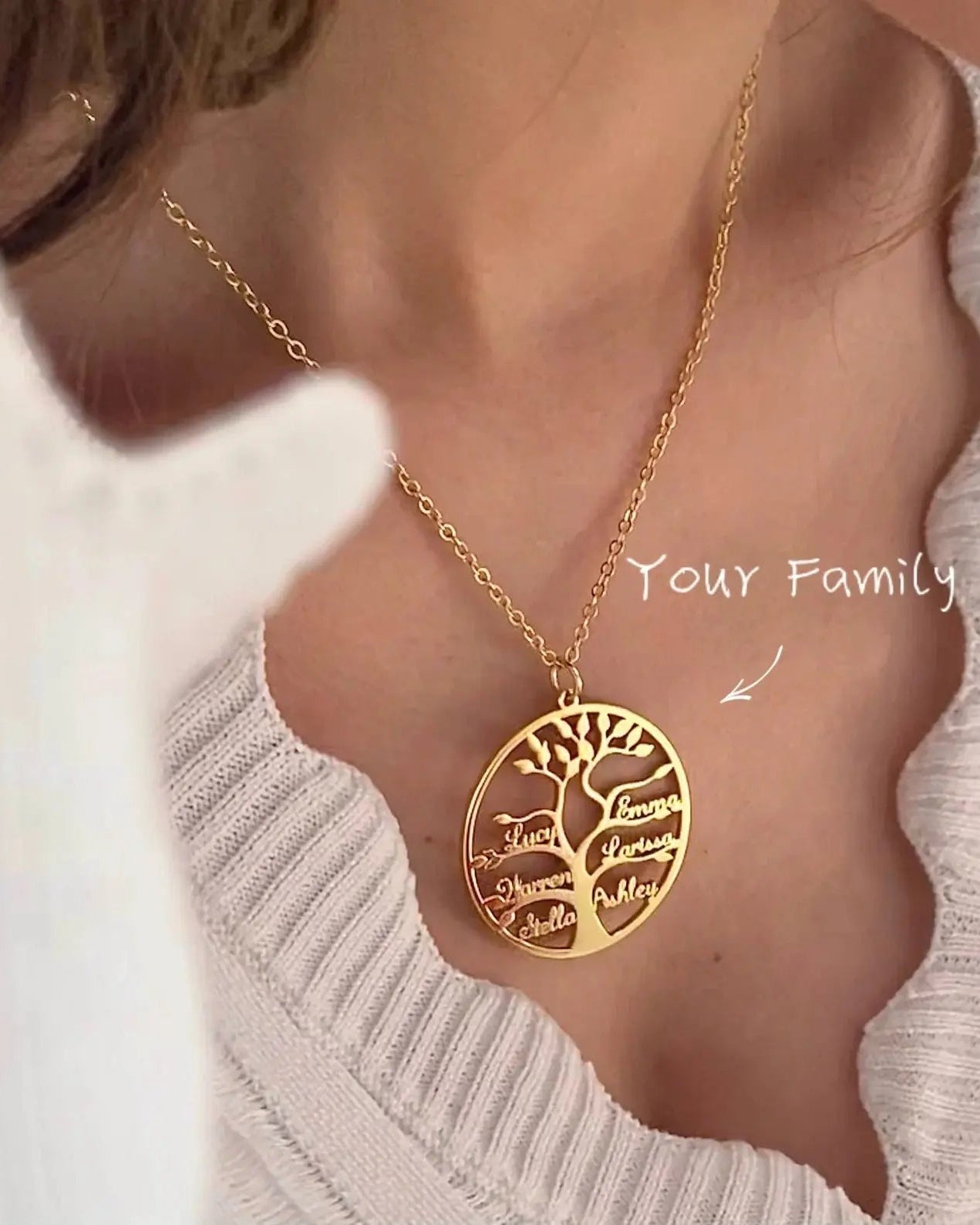 Gold necklace with a tree-shaped pendant on a person wearing a light gray sweater.