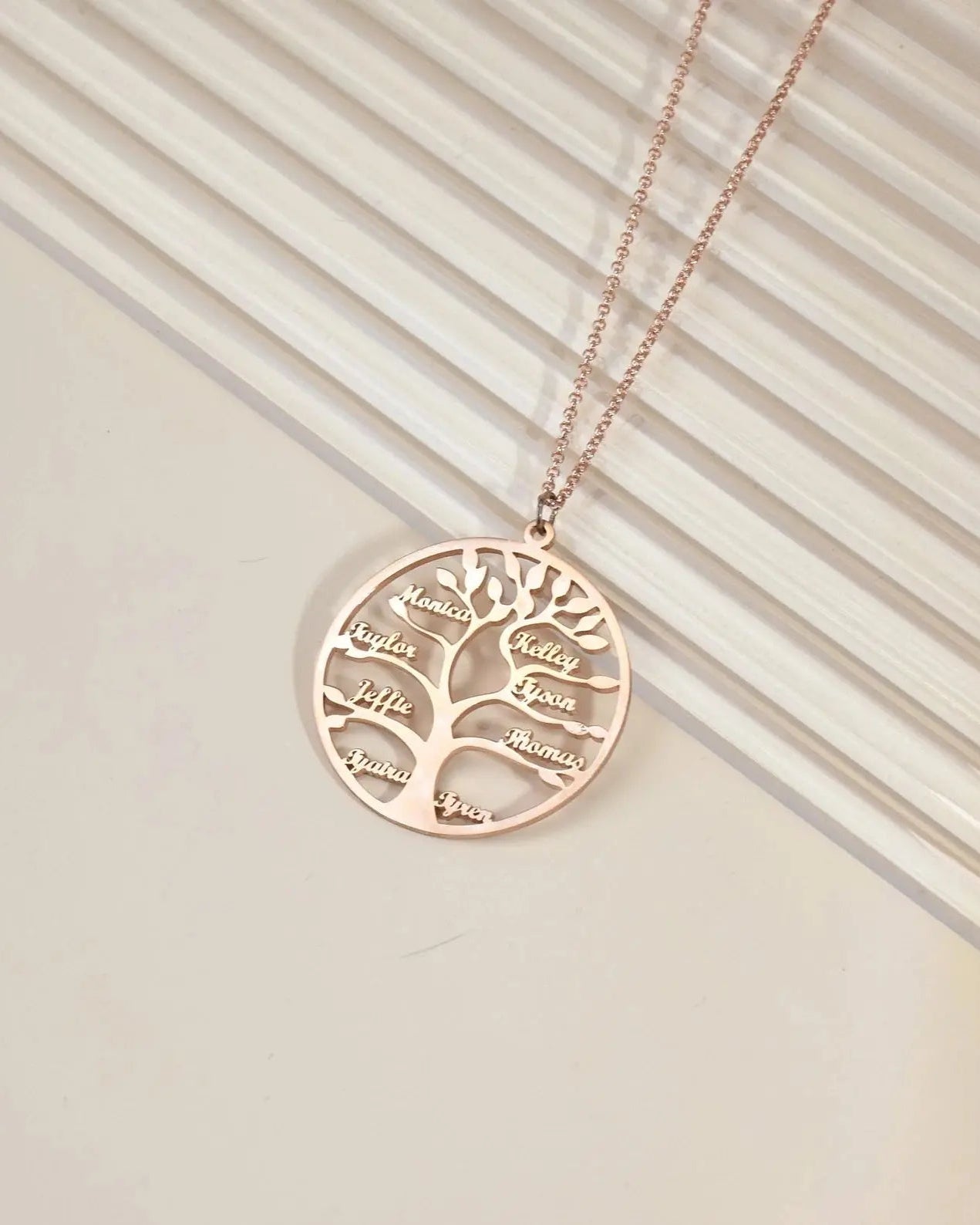 Rose gold family tree necklace on a neutral background