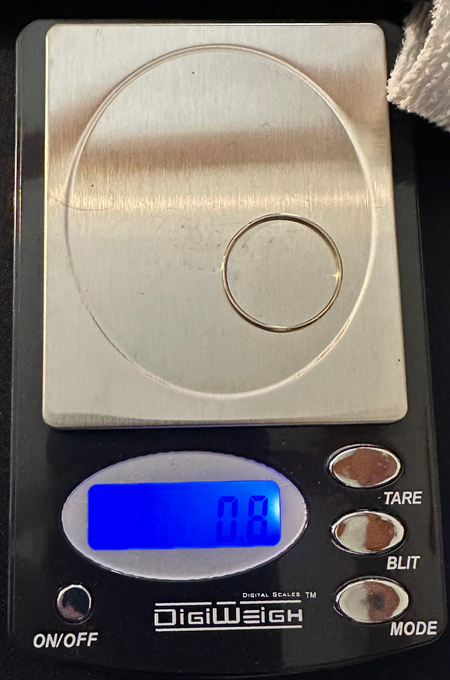 Professional jeweler's scale weighing a 0.8g solid 14K yellow gold stacking band for the Artisan Trio.