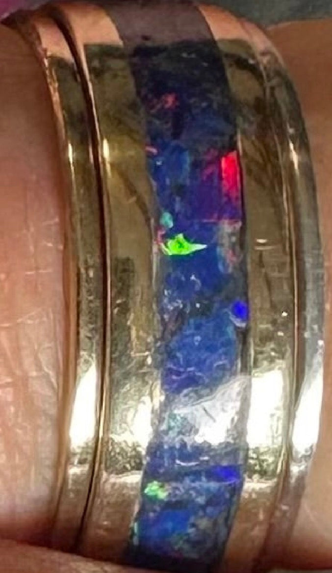 Close-up of hand-channeled electric blue fire opal inlay set in a 5.8g solid 14K yellow gold band. what with silver and gold stacking rings