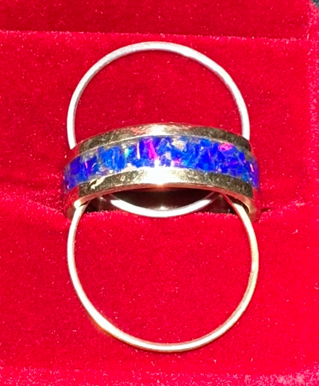 Ring with a colorful gemstone with two stacker rings one made of silver and one made of 14 karat gold on a red background