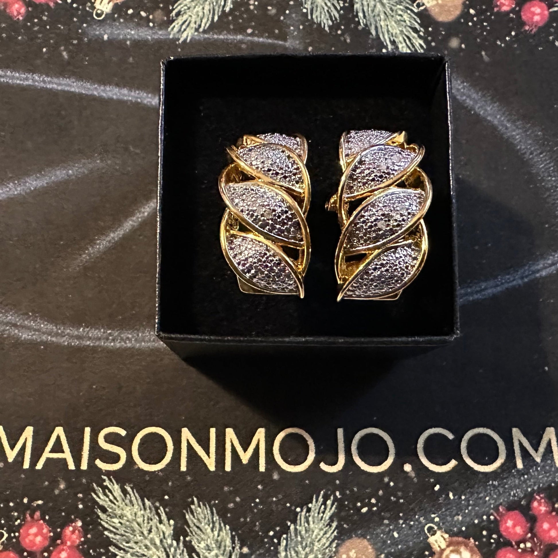 Gold and silver leaf-shaped earrings in a black box on a festive background with 'MAISONMOJO.COM' text.