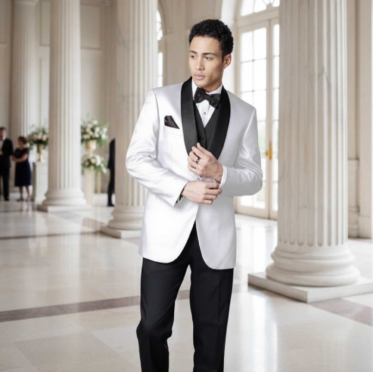 Man in a white tuxedo standing in a grand hall with columns