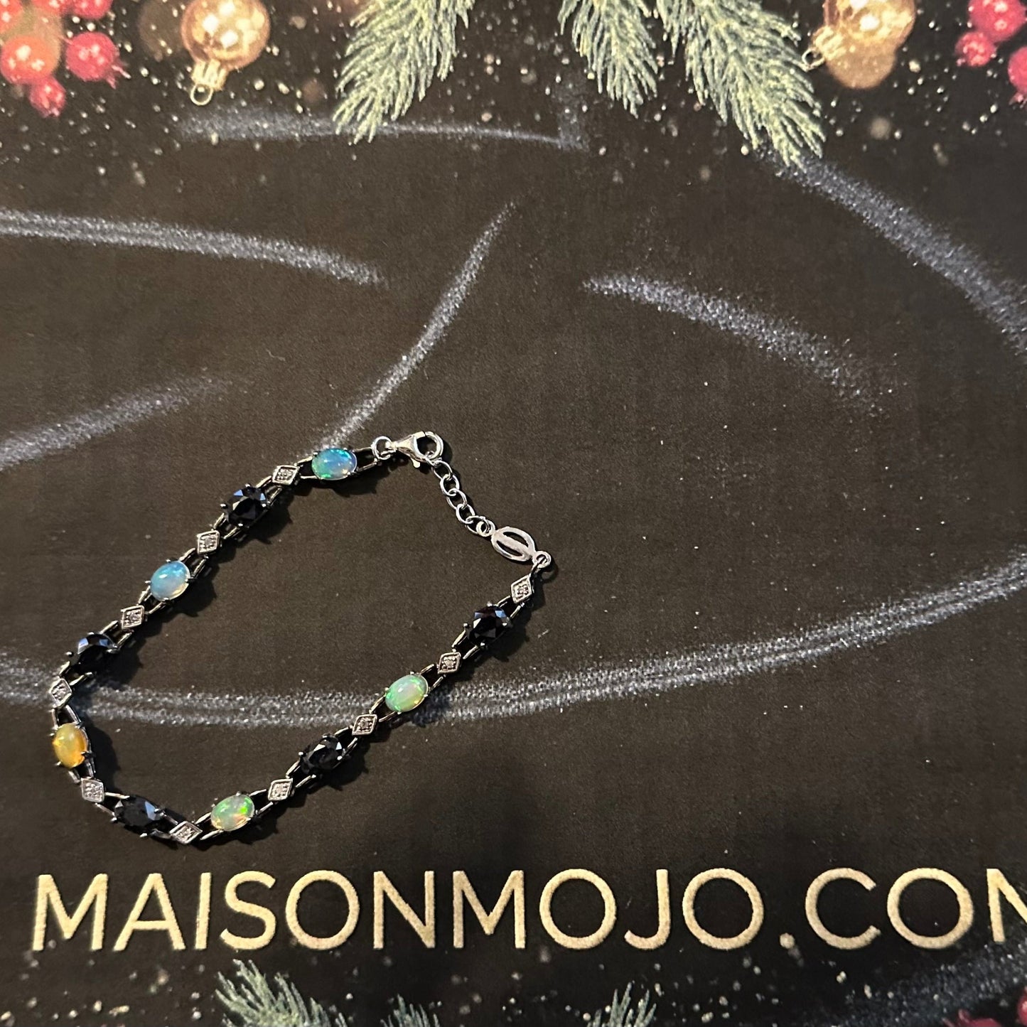 Bracelet with multicolored stones on a black background with 'MAISONMOJO.COM' text