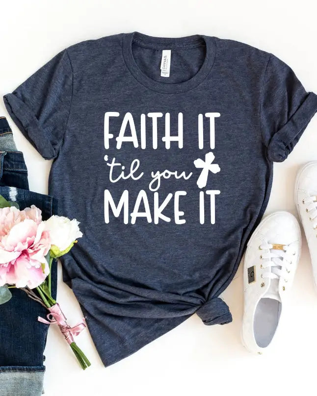Navy blue t-shirt with 'FAITH IT 'til you MAKE IT' text, white sneakers, jeans, and flowers on a white background