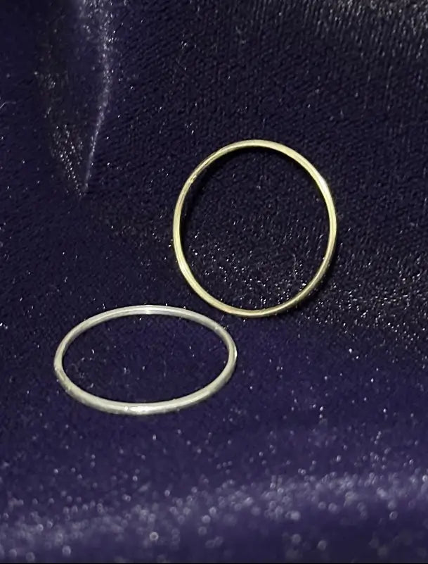 Two rings 1-14 karat gold 1-925 silver bling rings on a dark blue textured surface