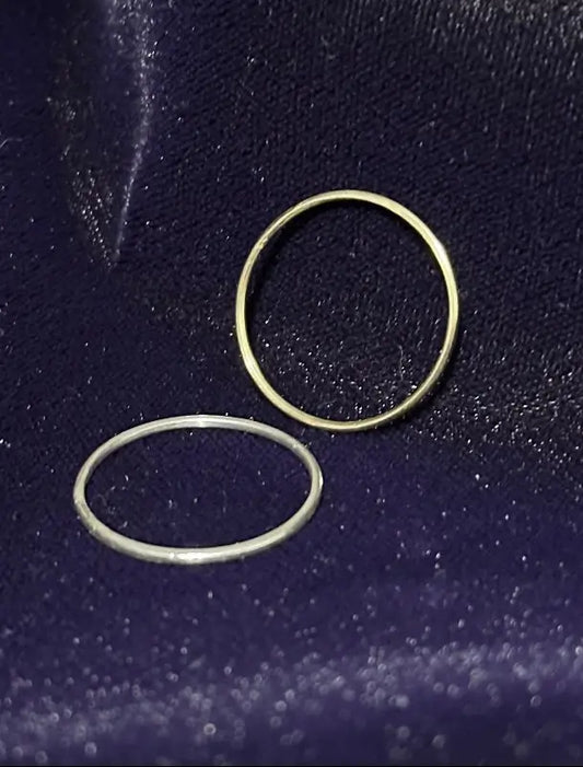 Two rings 1-14 karat gold 1-925 silver bling rings on a dark blue textured surface