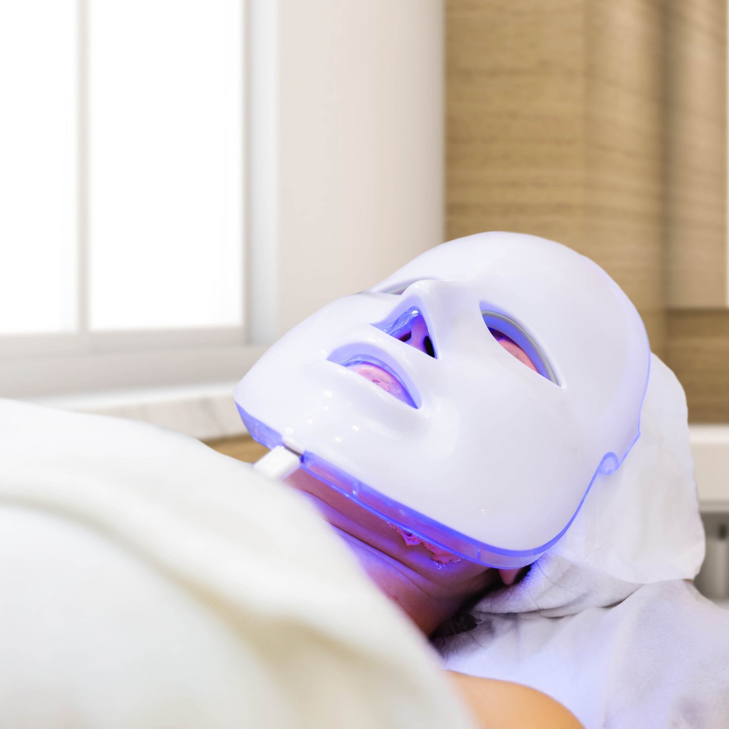 Professional skincare treatment featuring a person wearing a medical-grade LED mask while relaxing in a spa setting.