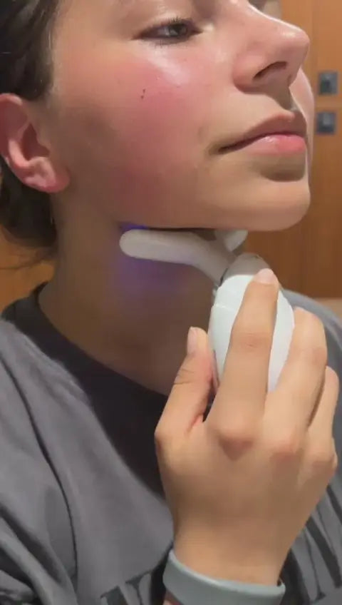 Woman using neck and face lifting therapy device for skin tightening and anti-aging massage. with a blue light on a white background