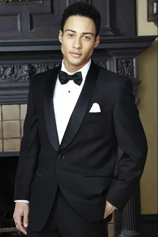 Man wearing a black tuxedo with a bow tie in an indoor setting.
