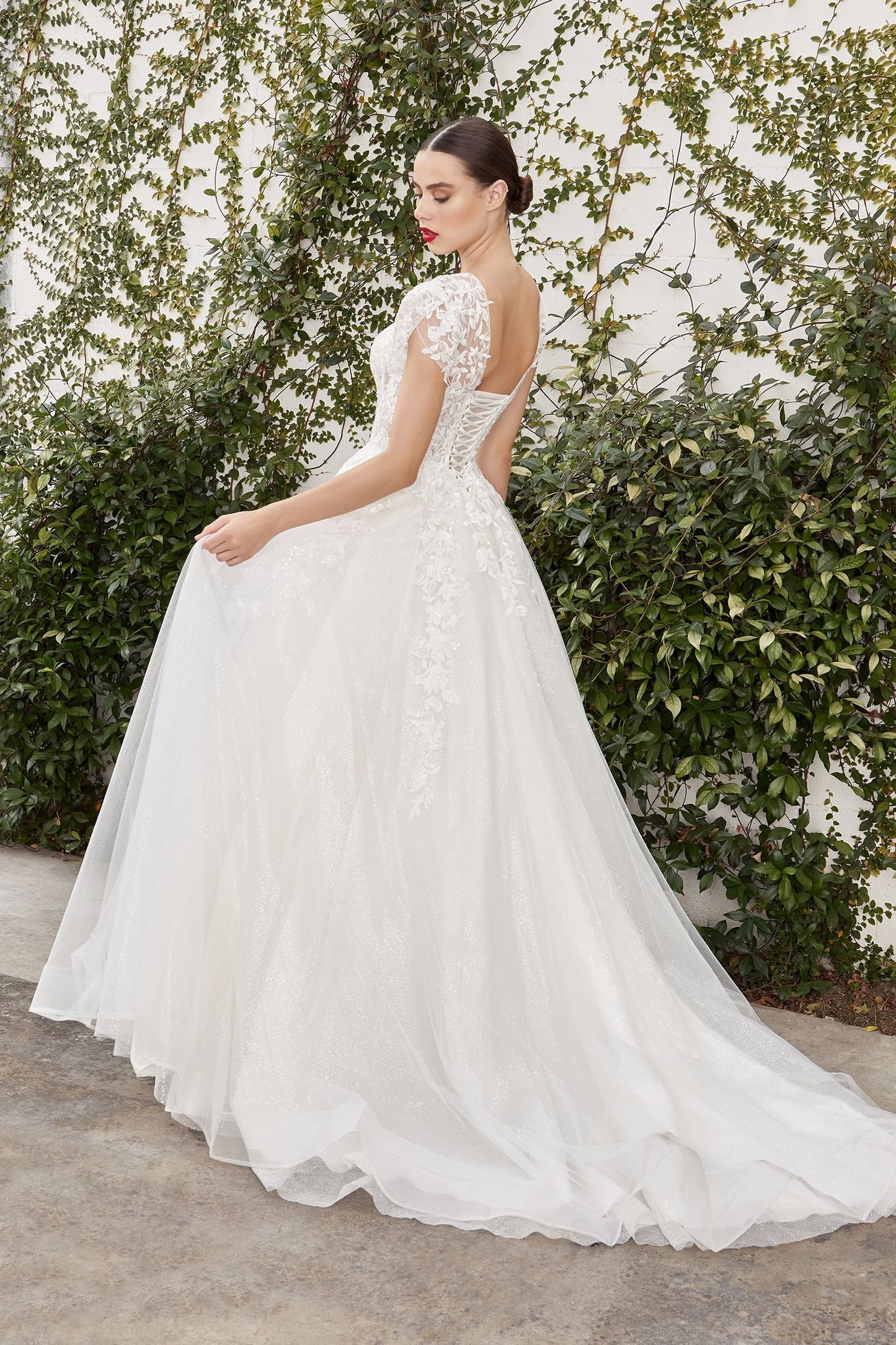 Woman in a white wedding dress standing against a green leafy background