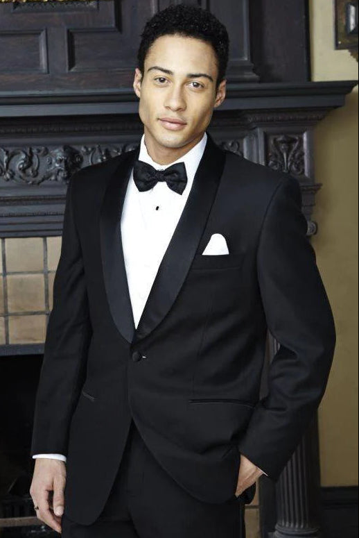 Man wearing a black tuxedo with a bow tie in an indoor setting.