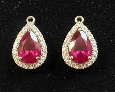 Two teardrop-shaped gemstones with gold accents on a black background