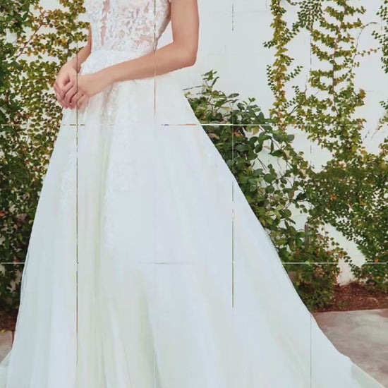 Woman in a white lace wedding dress standing outdoors with greenery in the background video 